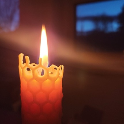 Beeswax candle lit in a dark room